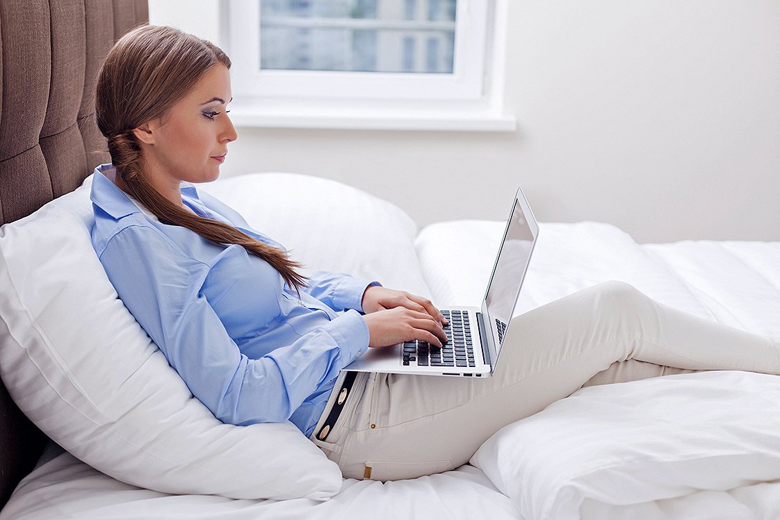 Close-up view of Woman using laptop on her bed