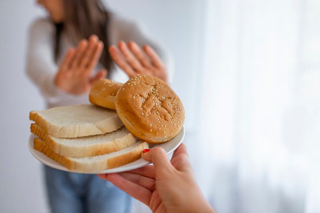 Young woman suffers from a gluten. Gluten intolerant and Gluten free diet concept, Real people. Copy space. Gluten intolerance and diet concept. Woman refuses to eat white bread. Selective focus on bread