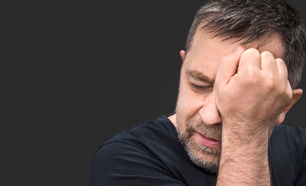 Headache. Portrait of an elderly man with face closed by hand on dark background with copy-space