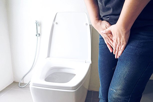 Woman holding hand near toilet bowl - health problem concept
