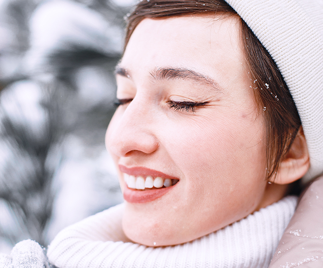 Close-up portrait of woman in brown kacket. Woman standing in snowy day.